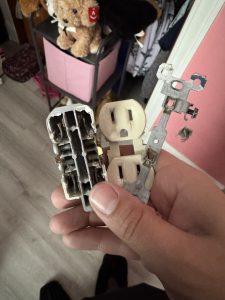 Old damaged electrical outlet held in a hand
